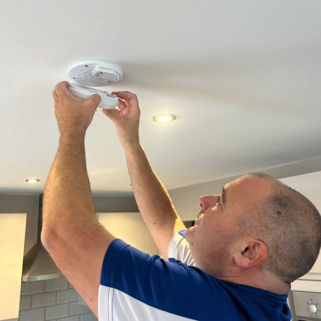 Smoke alarm being installed on a ceiling in Swansea
